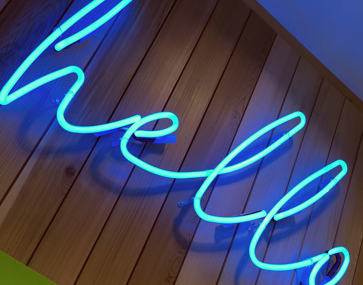 blue neon hello sign on cedar wood vertical panelling