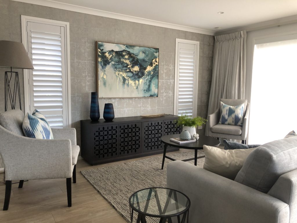 living room with black buffet unit, wood floors, gold and blue styling