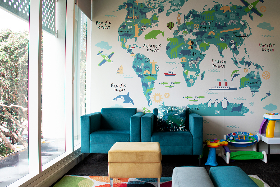 modern commercial lounge space with teal armchairs and world map wall decal