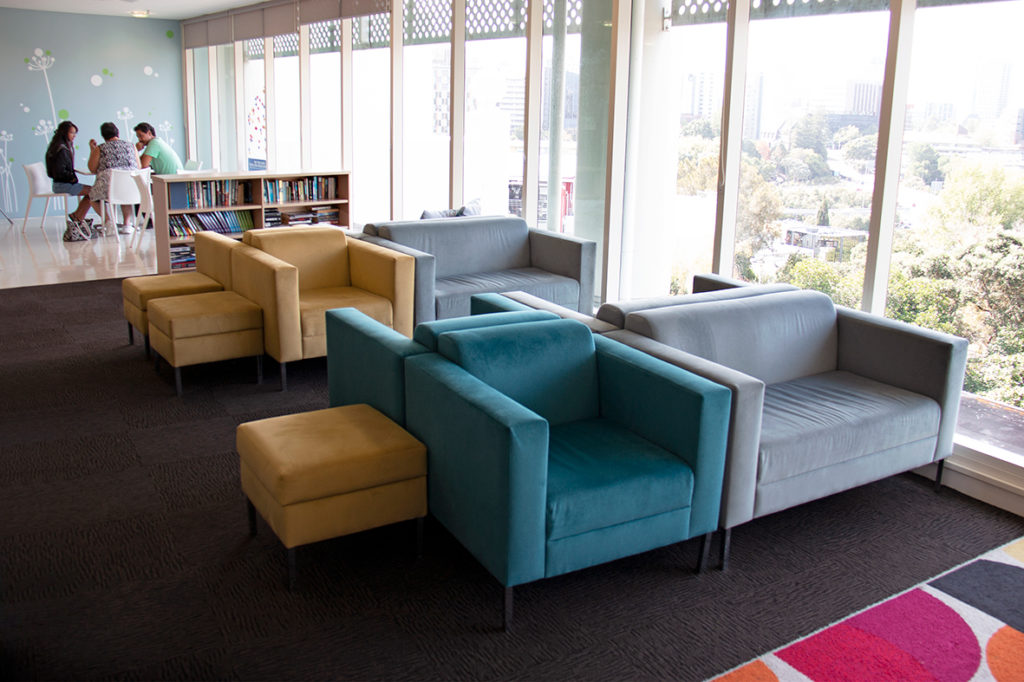 modern commercial lobby living room space with multi coloured furniture in teal, mustard and blue grey