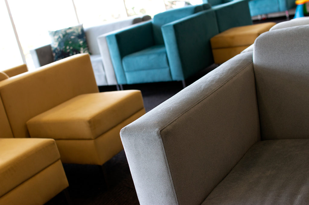 close up of modern armchairs in commercial lounge space with mustard, teal and grey colours