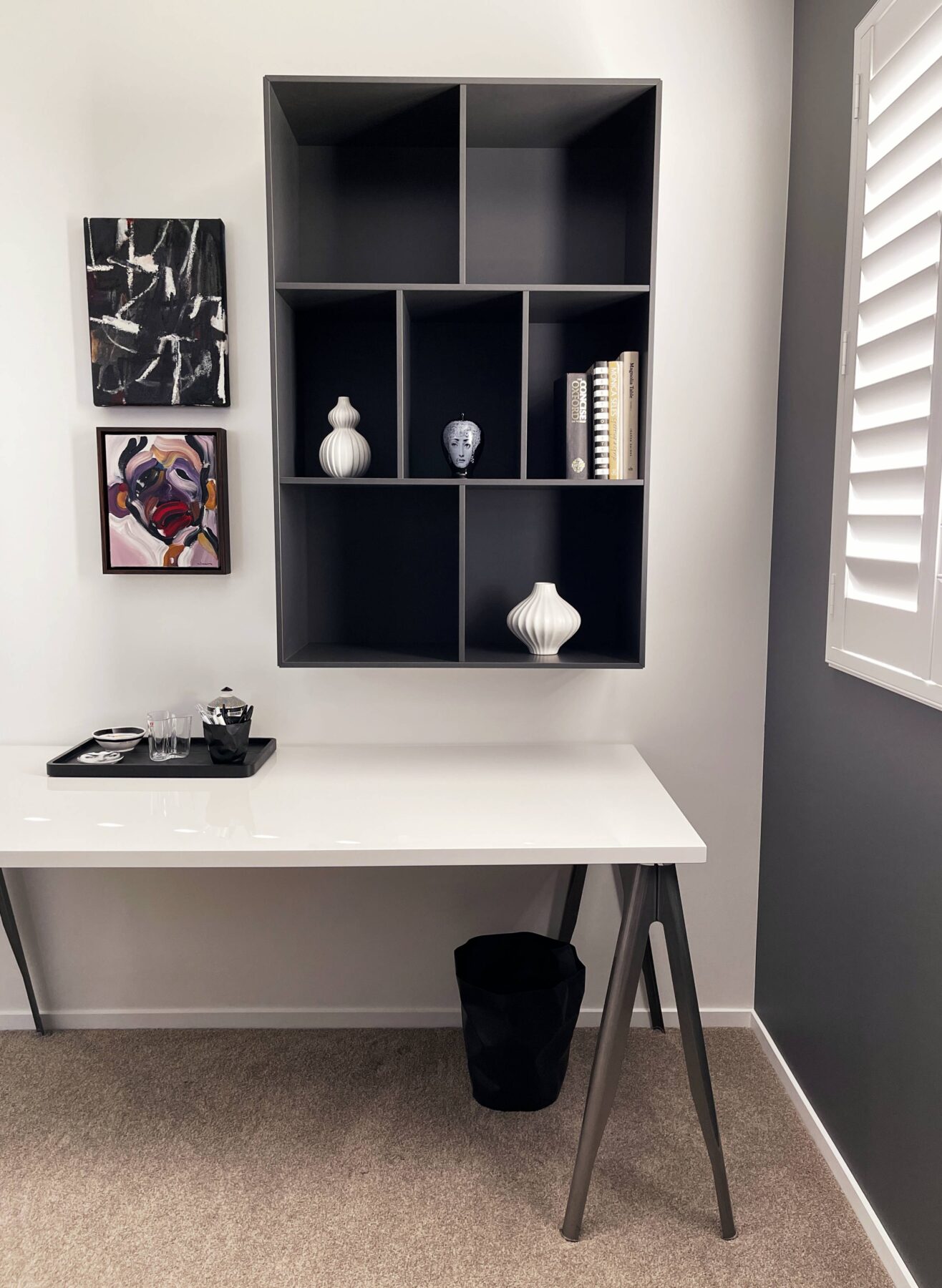 luxury monochrome office space, wall mounted hanging bookshelf, white desk with dark grey legs and simple styling, white window shutters, work from home