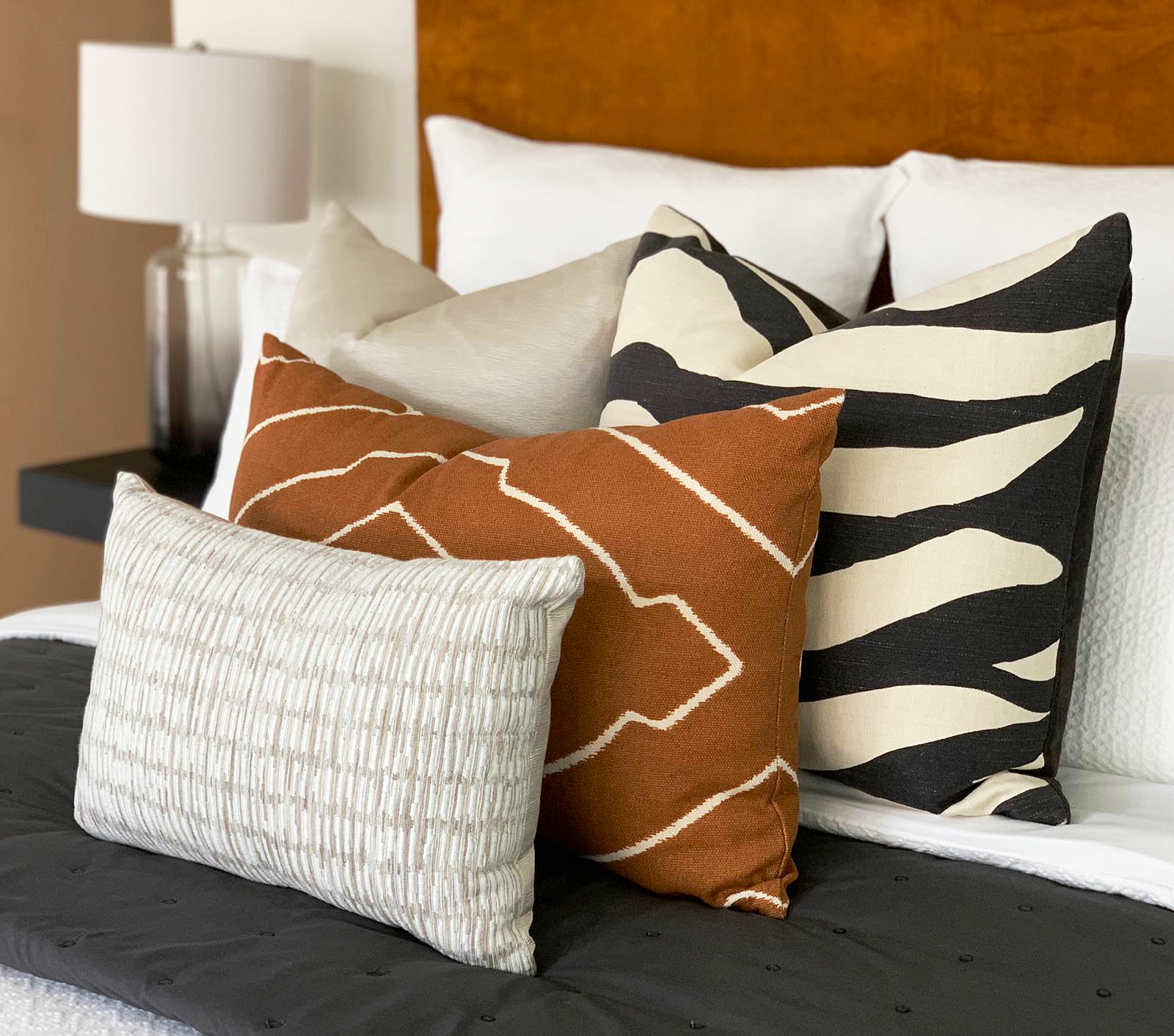 modern tribal bedroom with burnt orange and brown feature cushions and layers of texture