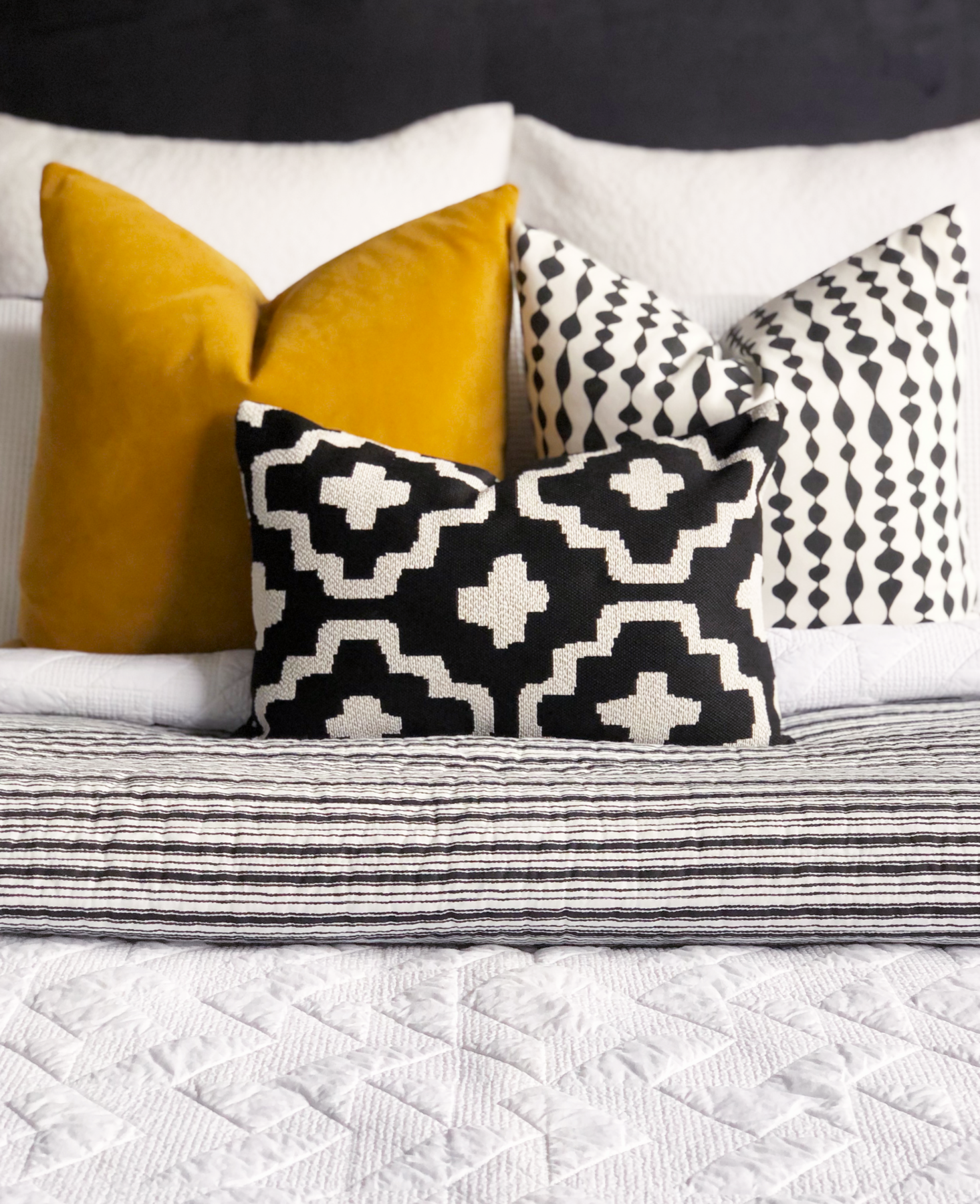 stylish bedroom with textured white linen, black, white and mustard feature cushions
