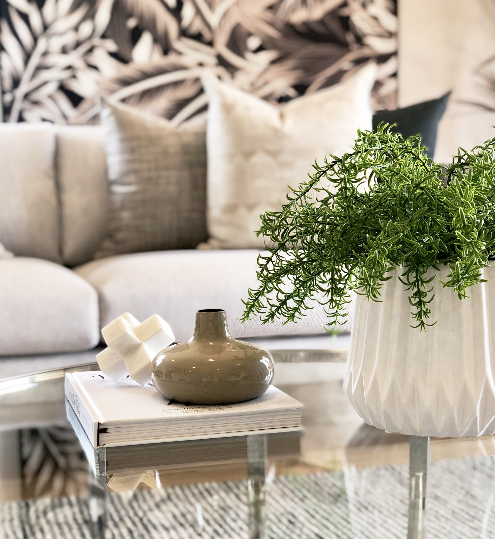 modern living room with silver and glass coffee table, plant styling and palm leaf wall art