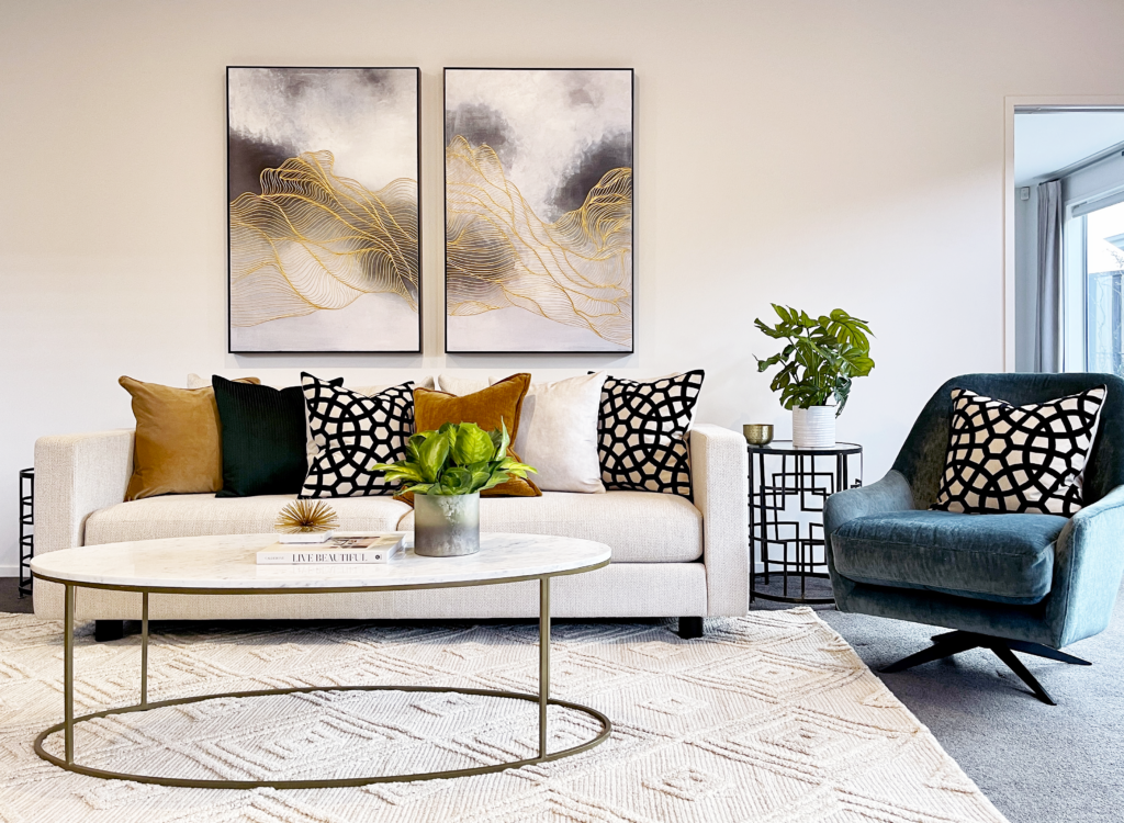 bright and fresh living room with blue black and gold highlights statement wall art and brass and marble coffee table